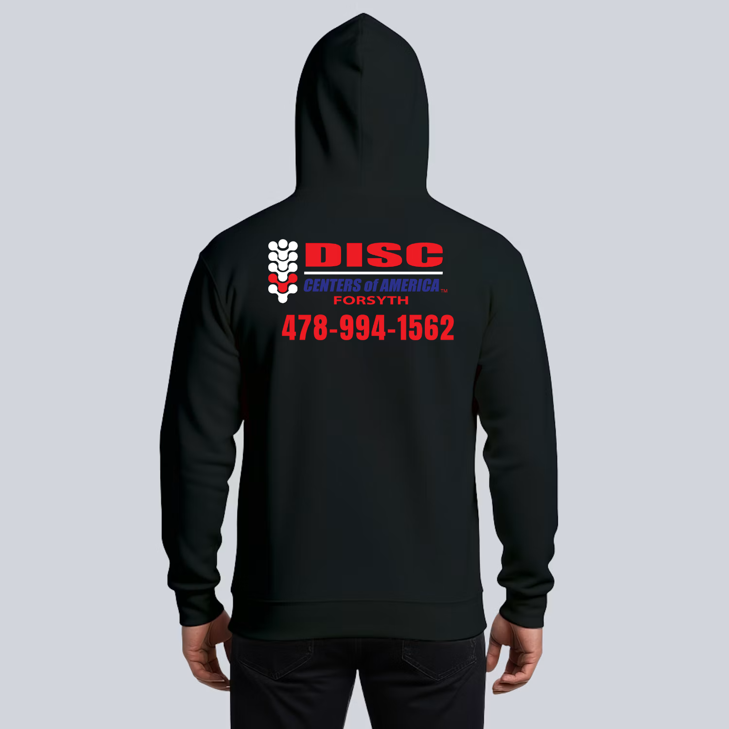 Project preview of the back of a dark hoodie with a large DISC Centers of America Forsyth logo and the client phone number below it.