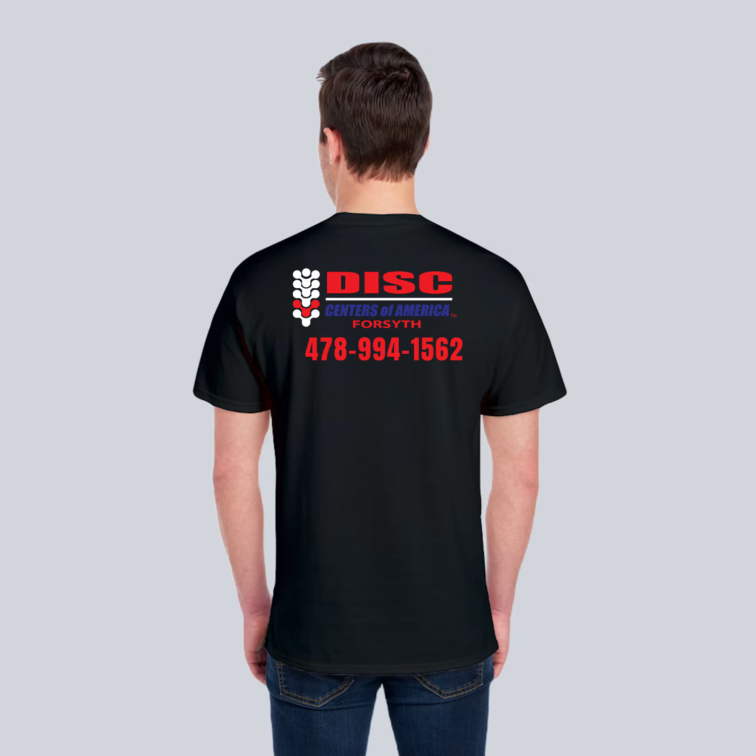 Project preview of the back of a dark short-sleeve shirt with a large DISC Centers of America Forsyth logo and the client phone number below it.