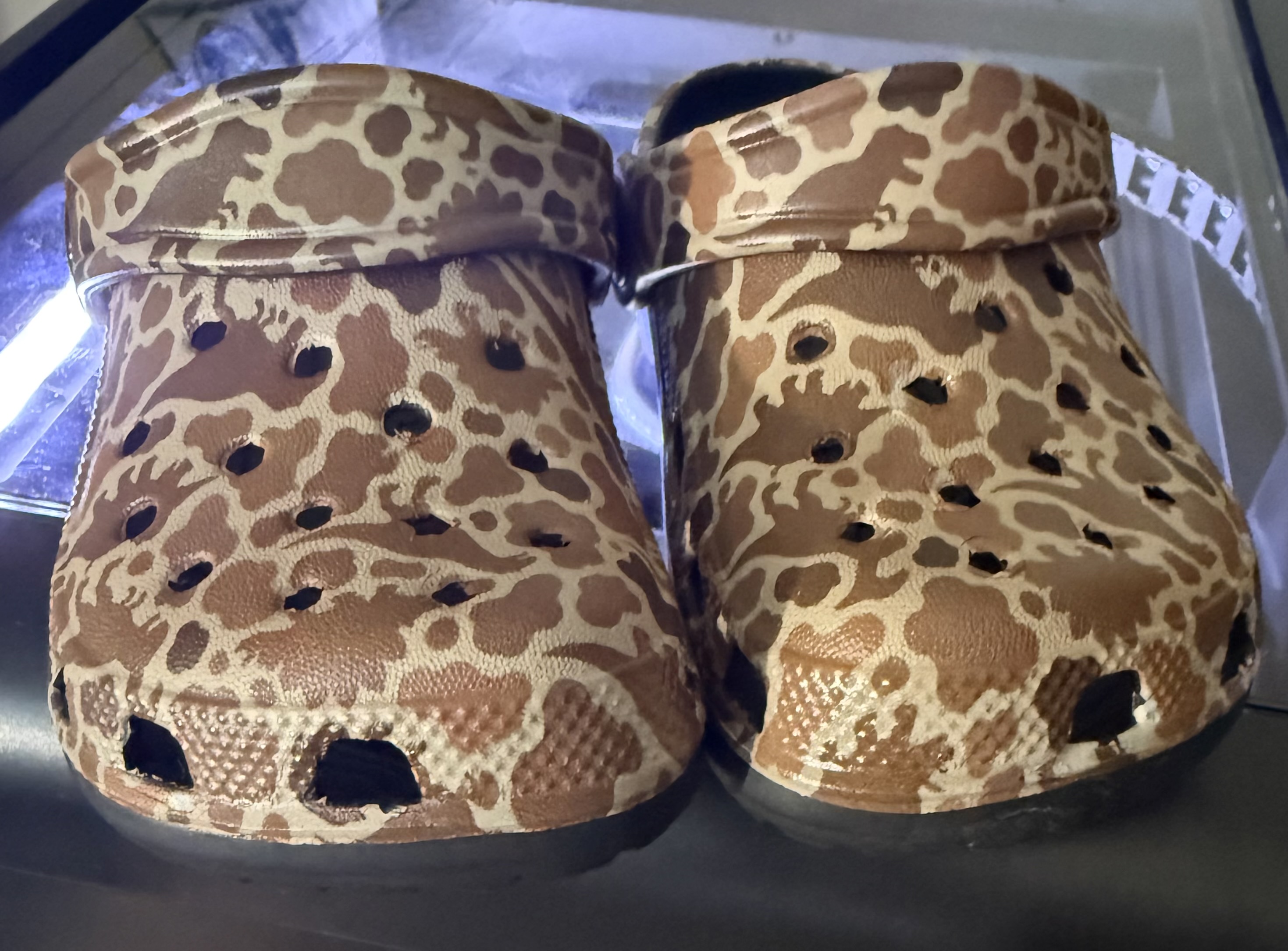 Customized Crocs with brown-and-tan dinosaur patterns.
